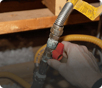 Hand turning red valve on metal pipe.