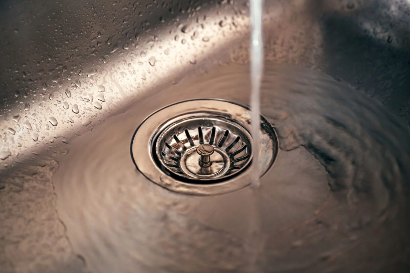 Water flowing into stainless steel sink drain.