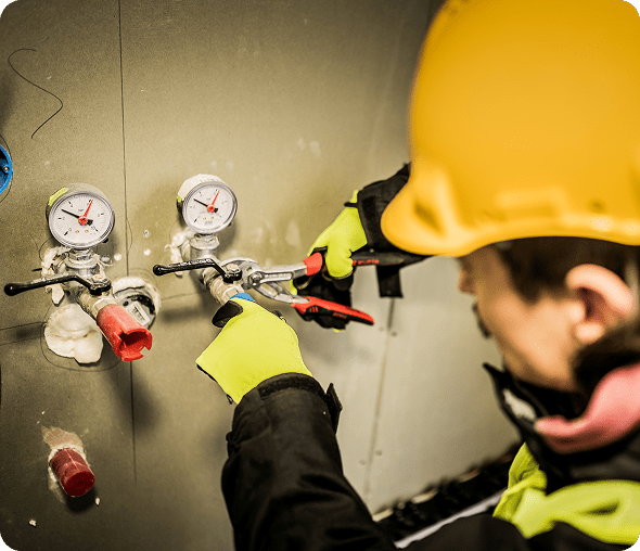 Worker adjusting valves with pressure gauges.