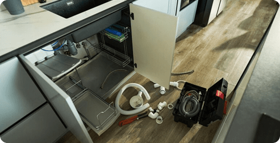 Kitchen sink plumbing tools and open cabinets.