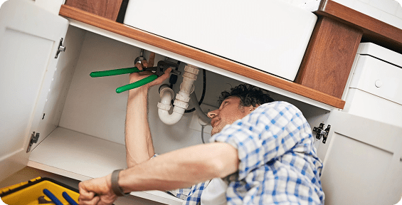 Plumber fixing pipes under kitchen sink.