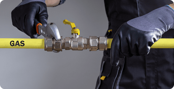 Worker adjusting gas pipe with wrench.