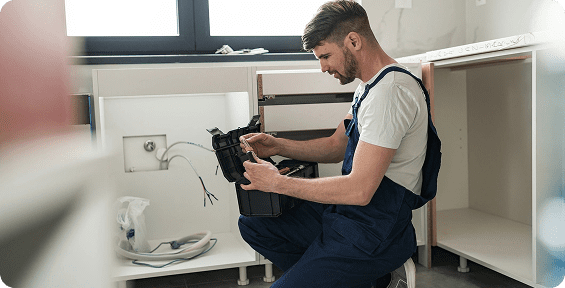 Plumber checking tools in kitchen cabinet.