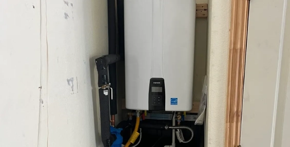 Modern tankless water heater installed on a wall with connected pipes.