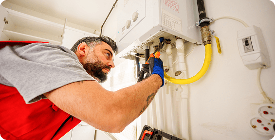 Plumber fixing a boiler with tools.