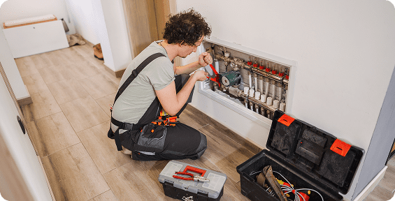 Plumber fixing pipes in a residential hallway.